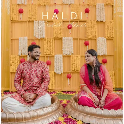 A happy couple seated in lotus-shaped pots during their 'phoolon ki haldi'. This shot captures the unique decor and joyful traditions of a modern haldi ceremony.