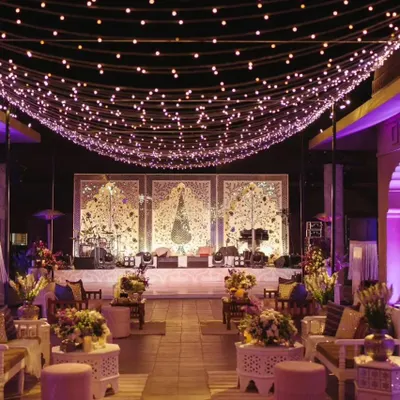 The entrance to a Sufi Night, featuring a canopy of fairy lights over a lounge-style seating area. The design uses white and lavender tones to create a serene and mystical vibe.