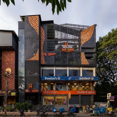 The completed facade transformation for 'High-drate' restopub. The new design uses a dynamic mix of materials including brick, perforated metal screens, and integrated greenery to create a bold, contemporary identity.