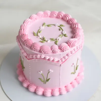 Isn't she lovely? This vintage-style cake features intricate piping, delicate floral details, and a unique hexagonal shape, all in a beautiful shade of pink. Inside is a rich Bailey's Chocolate flavor.