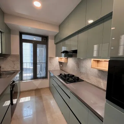 A modern parallel kitchen with a light green lacquered glass finish. The layout provides ample counter space on both sides, with integrated appliances and under-cabinet lighting for a bright and efficient cooking environment.