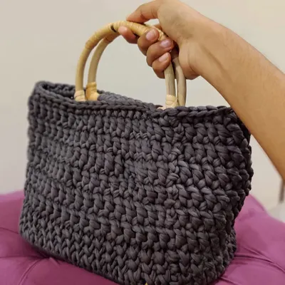 This T-shirt Yarn Basket Bag is made from chunky yarn, giving it a sturdy structure. It features a wooden base and smooth bamboo handles, perfect for carrying your daily essentials.