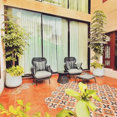This intimate patio corner features comfortable seating on a bed of vibrant, patterned terracotta tiles. The design blends traditional Moroccan aesthetics with modern comfort, creating a cozy nook for relaxation.