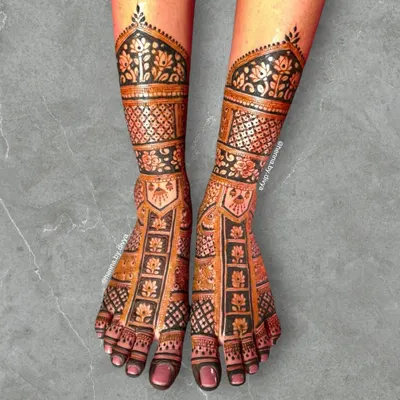 A full-coverage bridal feet design that is both intricate and bold. The design features panels of floral motifs and dense checkerboard patterns, extending up the ankle.