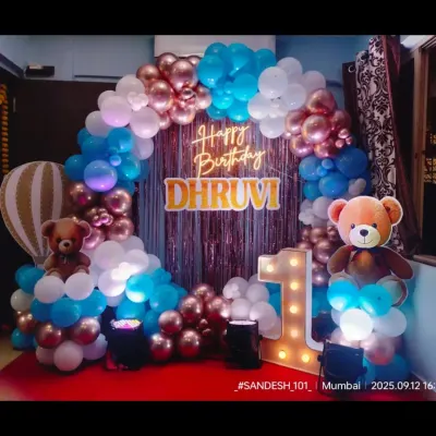 A beautiful circular balloon arch for Dhruvi's first birthday. The combination of rose gold, blue, and white balloons, along with cute teddy bears and a personalized neon sign, creates a warm and welcoming photo spot.