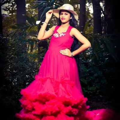 A striking solo portrait in a vibrant pink gown. The hat adds a touch of style, and the dark, moody lighting of the forest backdrop makes the subject and dress pop.