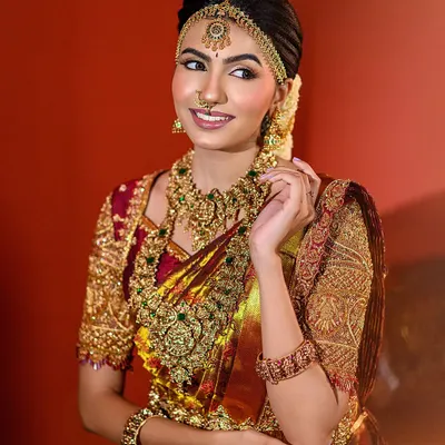 This is a signature Muhurtham look we created, focusing on a radiant bridal glow. I used soft lighting to complement the intricate gold jewelry and the rich texture of the silk saree, capturing a moment of serene happiness.