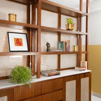The foyer cabinet was custom-designed with teak wood and woven cane panels. It provides storage while acting as a semi-transparent visual screen, defining the entryway without enclosing it.