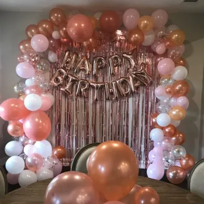 A full and luxurious balloon arch in shades of rose gold, pink, and white. This setup, complete with a foil curtain backdrop, transforms any corner of your home into an elegant party space.
