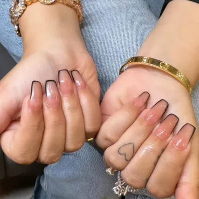 A chic and modern take on the French manicure. These long coffin nails have a sheer nude base with a sharp, thin black outline instead of a classic white tip.