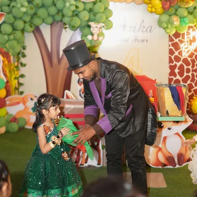 A magician captivates the birthday girl during her jungle-themed party. Live entertainment like a magic show is a fantastic way to keep all the young guests mesmerized.