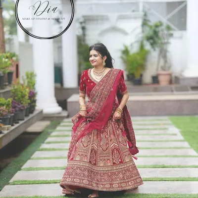 A full-length view of a bride in a magnificent red lehenga. The makeup is classic and elegant, designed to complement the grandeur of her outfit. This is a timeless North Indian bridal look, perfect for making a grand entrance.