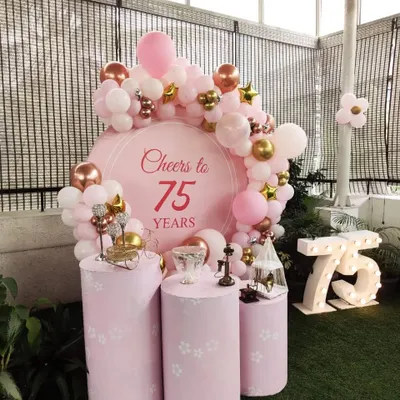 A beautiful 'Cheers to 75 Years' celebration, designed with a soft pink color scheme, elegant plinths, and a lovely balloon garland.
