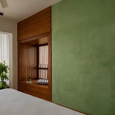 A cozy window seat, framed entirely in wood, is integrated into the bedroom wall. This 'bay window' nook offers a private space for reading and reflection, connecting the room with the outdoors through a slatted screen.