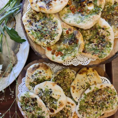 A beautiful platter of our assorted homemade kulchas, featuring a variety of toppings like herbs, spices, and chili for a diverse bread basket.