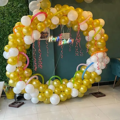 This beautiful balloon ring in gold and white is perfect for birthdays or anniversaries. The setup is enhanced by a custom 'Happy Birthday' neon sign that adds a colorful glow.
