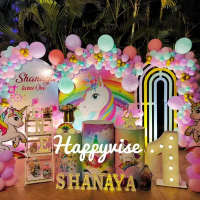 A magical unicorn party for Shanaya's first birthday. The setup is full of pastel rainbows, unicorn cutouts, and a large light-up number "1" for a truly enchanting celebration.