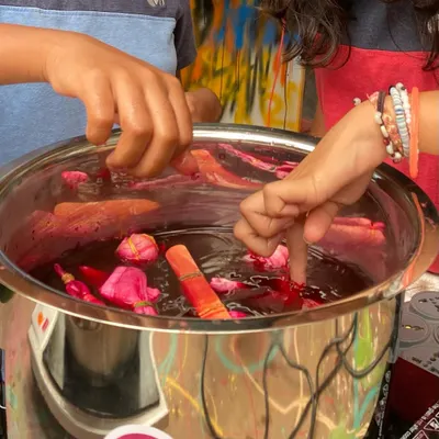 A close-up of our natural tie-dye workshop. Participants are dipping their bundled fabric into a dye bath made from natural ingredients. It is a magical process to watch the colours take hold.