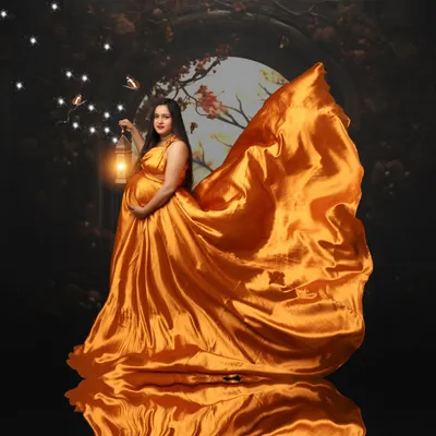 A mother's glow truly lights up the world. This portrait captures that magical feeling with a flowing golden gown and a lantern to guide the way, reflecting the beautiful journey of creating life.