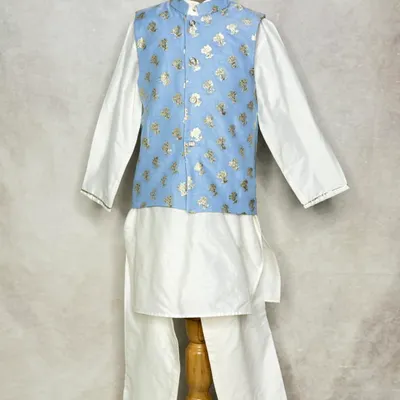 A classic white kurta pajama set gets an upgrade with this powder blue floral brocade Nehru jacket. It's a smart and stylish look for any young gentleman.