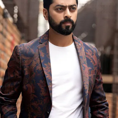A strong portrait of actor Tarak Ponnappa. The combination of a floral blazer, a simple white tee, and a gritty urban background creates a modern and stylish look.