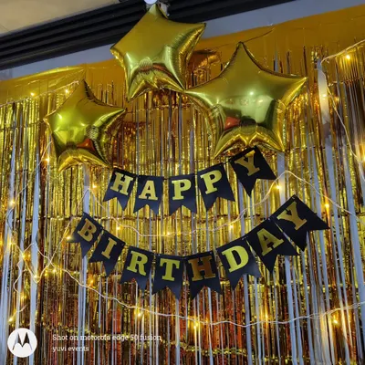 A classic and affordable birthday backdrop. This setup includes a gold foil curtain, a 'Happy Birthday' banner, star-shaped foil balloons, and fairy lights.