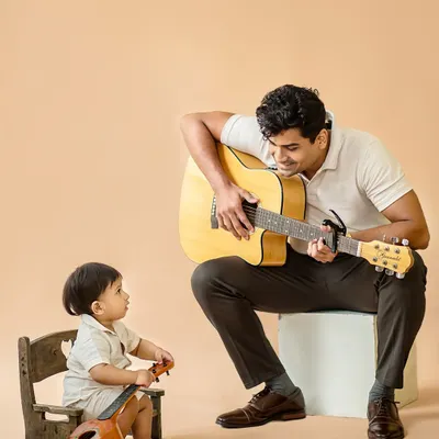 A heartwarming studio moment between an uncle and his nephew, sharing a love for music. The little one looks on in admiration, creating a beautiful, candid portrait.