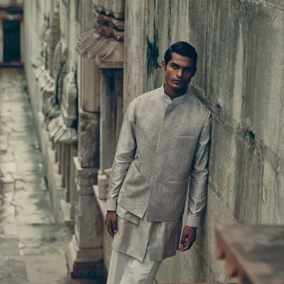 A full look from the Dhruv Vaish campaign, shot in a historic stepwell. The layered grey and white ensemble stands out against the ancient stone, creating a look that is both modern and timeless.