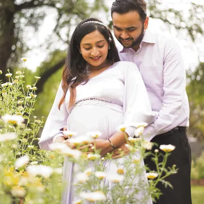 A beautiful candid moment between expectant parents, surrounded by wildflowers in a sunlit garden. I love capturing these shared glances and gentle interactions that tell the story of their journey together.