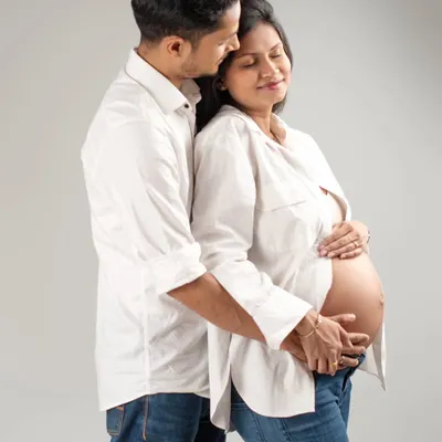 A quiet, intimate moment shared between partners. I gently guide couples into poses that feel natural, capturing the love and support that surrounds your growing baby bump in a simple, classic studio setting.