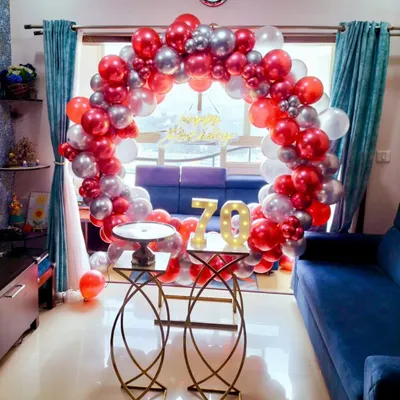 A dazzling 70th birthday home decoration featuring a red and silver balloon ring and large light-up marquee numbers. This setup transforms a living room into a festive party space.