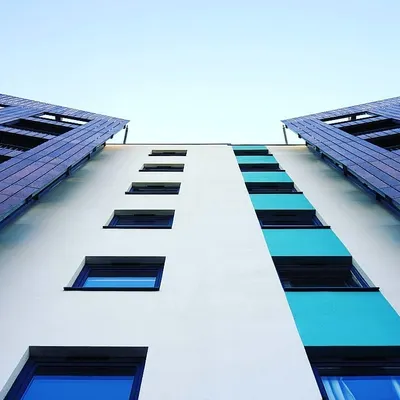 An upward view of a modern apartment building's exterior. I use high-quality exterior paints to create striking designs and protect the building from the elements.