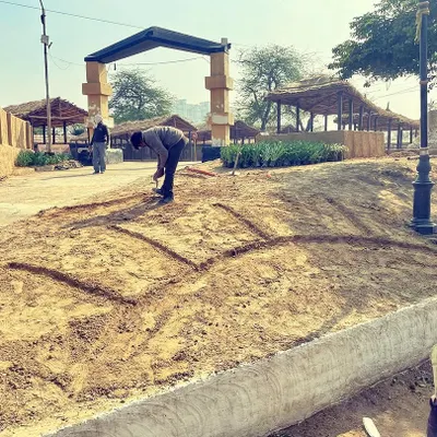 The first step in our community greening project at the Surajkund Mela. Here, I am carefully marking out the pattern for a large floral display directly onto the prepared soil bed before we begin planting.