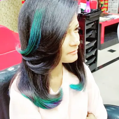 A pop of color can transform your entire look. Here, I've added vibrant teal and purple peekaboo highlights to a layered cut for a fun and edgy style.