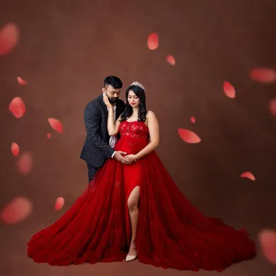 A truly romantic maternity portrait featuring a flowing red gown and delicate petal effects. This fine-art style creates a dreamy, painterly image that celebrates the magic of pregnancy.