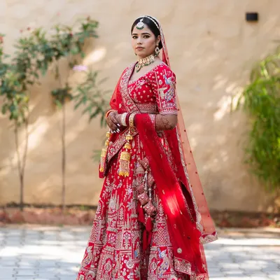 A stunning full-length portrait of the bride, Priya, in her magnificent red wedding lehenga. I focus on classic poses that highlight the beauty of the bridal attire.