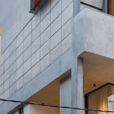 A detail of the exterior facade, showing the sharp lines of the concrete volumes. The grid-patterned concrete panels add texture and a sense of crafted detail to the brutalist-inspired form.