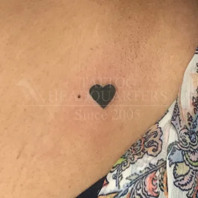 A tiny, solid black heart tattoo on the collarbone. This minimalist design is a perfect example of a simple yet meaningful piece.