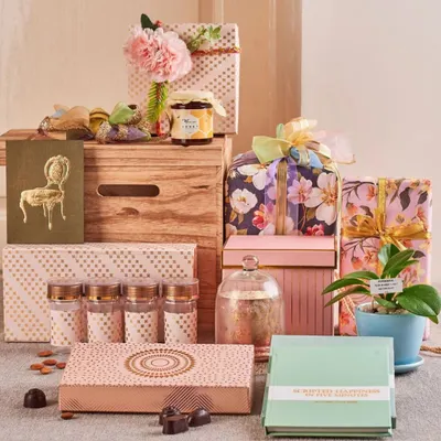 This festive hamper is curated for Diwali, featuring a mix of modern and traditional items. It includes dry fruits, chocolates, a live plant, and beautifully wrapped gift boxes in floral and polka-dot prints.