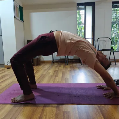 A student finds their arch in Chakrasana (Wheel Pose). This powerful backbend opens the heart, strengthens the arms and legs, and energizes the entire body.