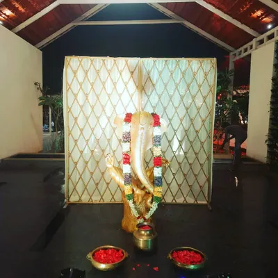 A Ganesha idol placed at the entrance of an event, set against a simple backdrop. This setup is ideal for welcoming guests and invoking blessings for a wedding or puja.