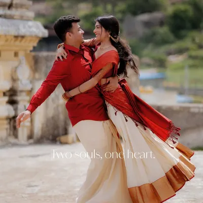A couple shares a joyful, spontaneous dance at Melukote, their traditional red and white outfits flowing with the movement. This is a perfect example of capturing unposed happiness against a historic backdrop.