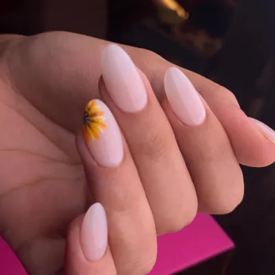A touch of sunshine for your fingertips. This minimalist design features a delicate, hand-painted sunflower on a single accent nail, set against a clean, milky-white base on beautifully shaped oval nails.