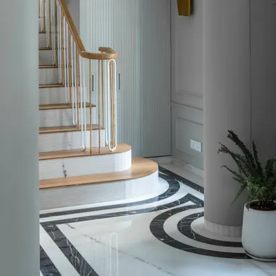 The staircase at Summer Haus is the metaphorical spine of the home, its elegant curve and marble detailing creating a sense of rhythm as it connects the public and private floors. The custom brass and wood railing is a testament to our focus on bespoke craftsmanship.
