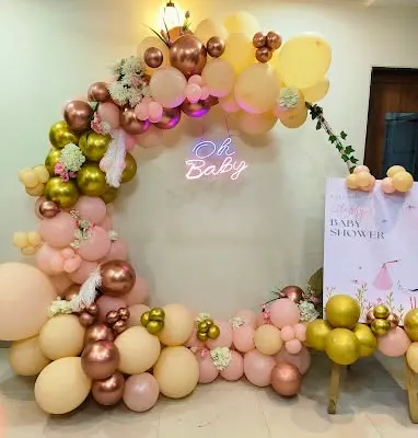 A popular choice for baby showers, this circular balloon arch features an "Oh Baby" neon sign. The color palette of peach, rose gold, and soft yellow creates a warm and celebratory atmosphere, complemented by a matching welcome sign.