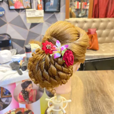 A creative updo on a mannequin, showcasing a twisted bun technique decorated with flowers. This is a style I teach in my advanced classes.