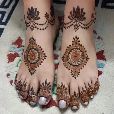 An elegant and symmetrical foot mehndi design. This pattern features mandalas on the feet, lotus chains around the ankles, and detailed work on all the toes.