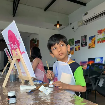 A young artist deep in thought, contemplating his next brushstroke. It's pure joy watching young minds dive into a world of color and creativity.