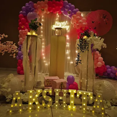 An elegant and mature setup for Akshita's 12th birthday. The theme uses a pink and lilac color palette with cherry blossom details, a 'Happy Birthday' neon sign, and light-up marquee letters.