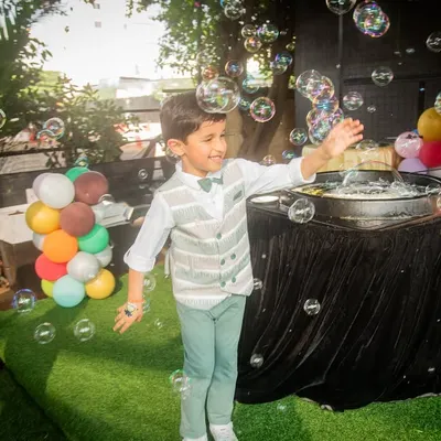 Pure joy. The birthday boy has a blast playing with a bubble machine, a perfect candid moment from his outdoor party.